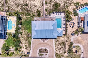 An aerial view of a resort with multiple swimming pools, a central building with a blue roof, and surrounding landscaped areas. - Sugar Magnolia! Beach Front, Private Pool, Free Beach Gear! (St. George Island)