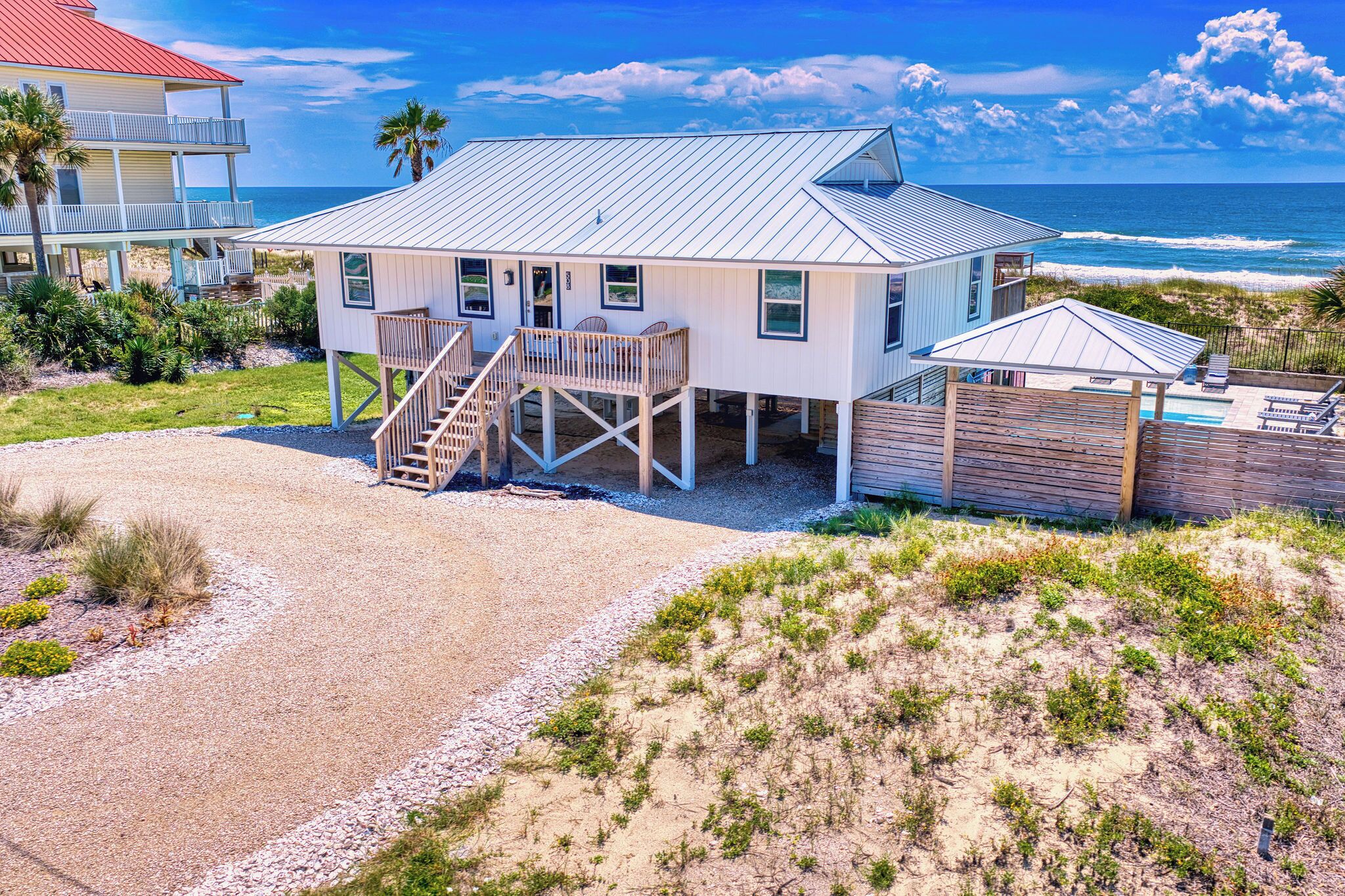 A beachfront house with a deck, a staircase, and a pool area.