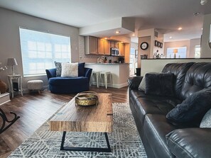 A modern living room with a leather couch, a blue sofa, and a coffee table.