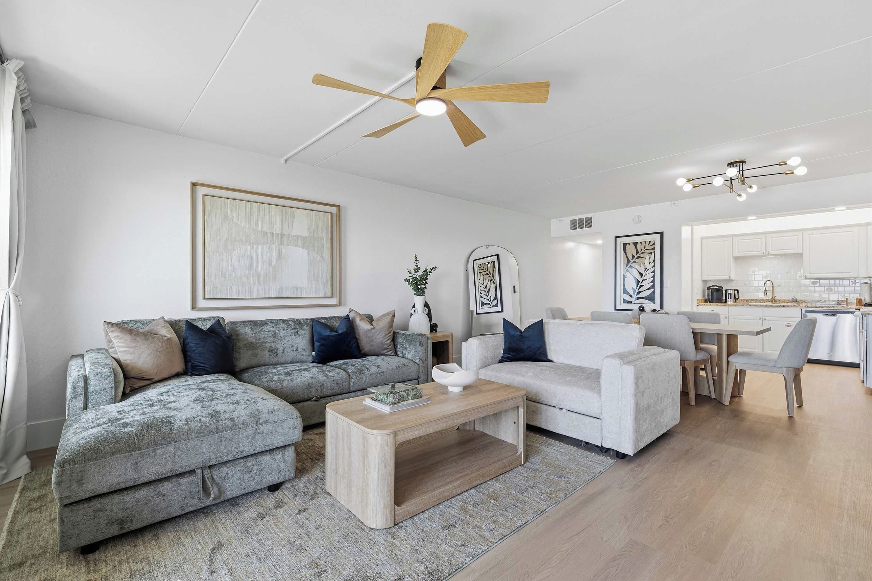 A modern living room with two sofas, a coffee table, and a ceiling fan.