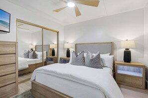 A hotel room with a large bed, two bedside tables with lamps, a ceiling fan, a large mirror, and a framed picture on the wall. - Gulf Front Condo w Pool, Tennis Courts & more! (Fort Walton Beach)
