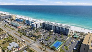 An aerial view of a coastal hotel with a beach view, parking lots, and a tennis court. - Gulf Front Condo w Pool, Tennis Courts & more! (Fort Walton Beach)