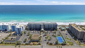 A hotel with multiple buildings, a parking lot, and a beach in the background. - Gulf Front Condo w Pool, Tennis Courts & more! (Fort Walton Beach)