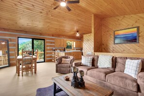 A wooden interior with a sofa, dining table, and kitchen area.
