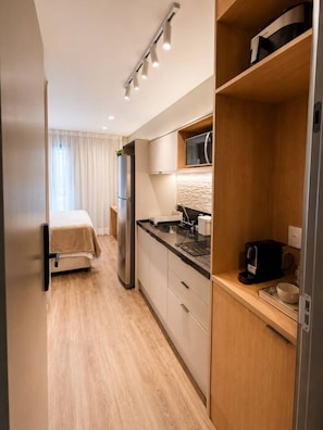 Eine moderne Küche mit integriertem Mikrowellenherd, einer Kaffeemaschine und einem Kühlschrank.