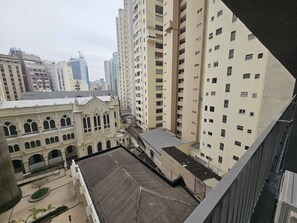 Un immeuble de grande hauteur, doté de nombreux étages, un patio avec une fontaine, et des bâtiments plus anciens adjacents, caractérisés par des fenêtres en arc de cercle.