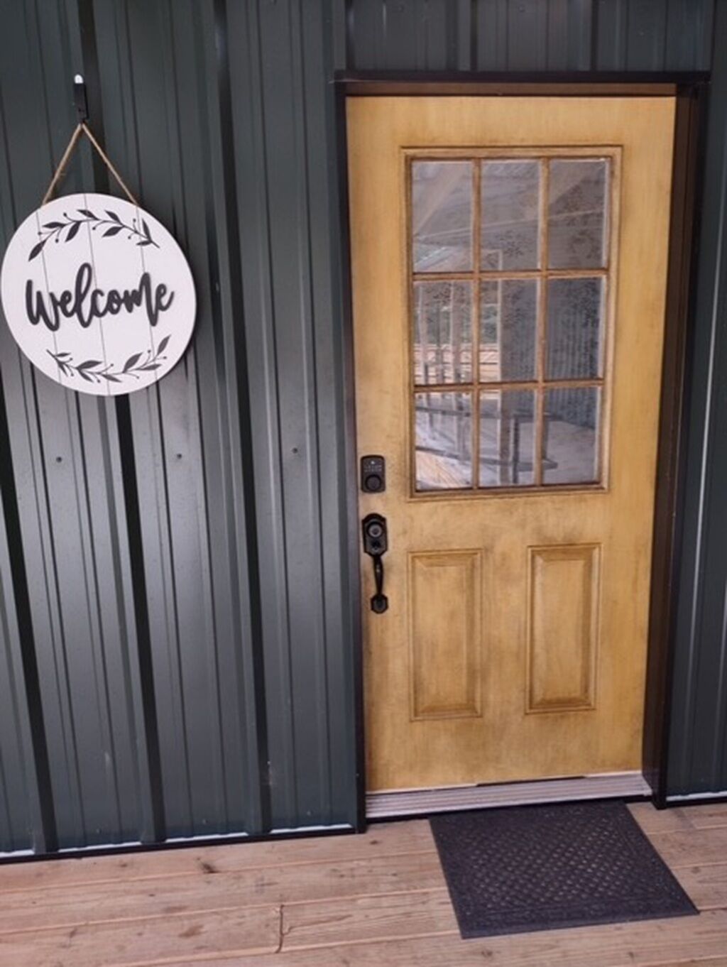 A wooden door with a glass panel and a welcome sign.