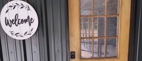 Puerta de madera con un panel de vidrio y un cartel de bienvenida.