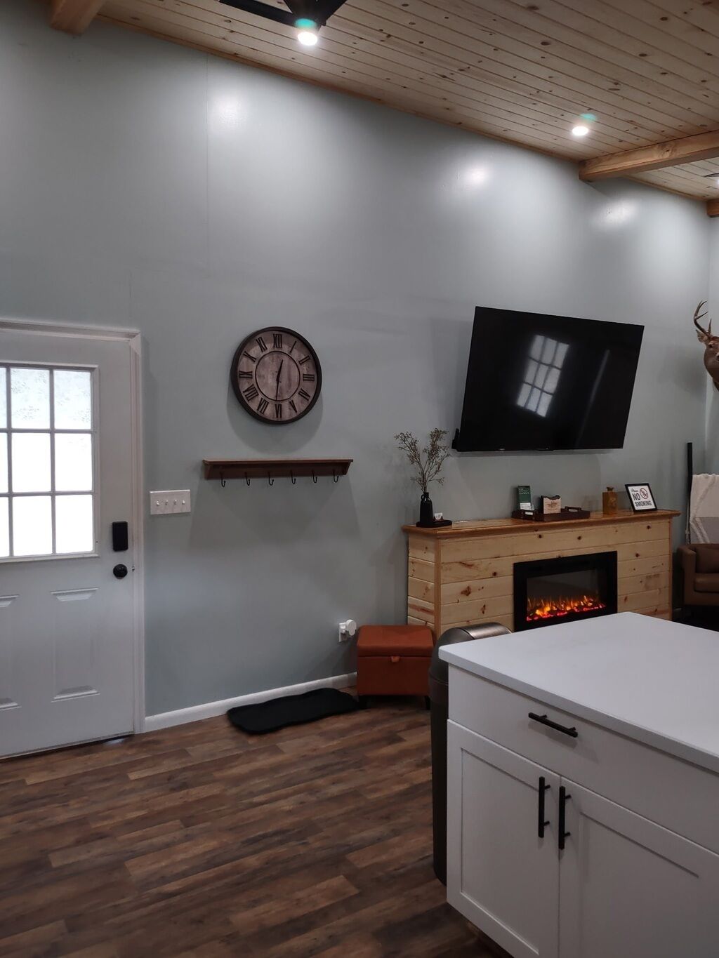 A room with a fireplace, a mounted television, and a clock on the wall.