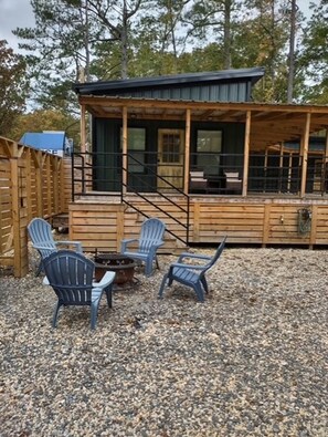 A wooden deck with a covered seating area, outdoor chairs, and a fire pit.