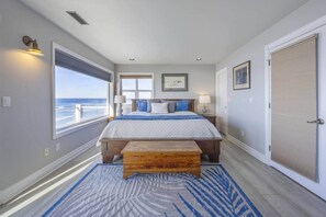 Une chambre à coucher avec un grand lit, un banc, une fenêtre donnant sur un beau paysage et une porte.