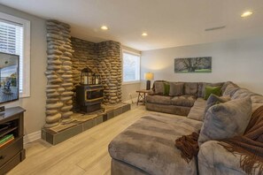 A living room with a stone wall, a fireplace, a sofa, and a television. - Sanctuary at Seal Rock (Seal Rock)