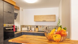Una cucina moderna con un piano di lavoro in legno, una grande ciotola di frutta e un forno a microonde.