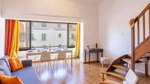 Ein modernes Wohnzimmer mit einer Couch, einem Esstisch, Stühlen und einer Holztreppe.