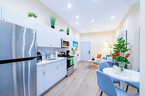 A modern kitchen with a refrigerator, microwave, and stove. There is a dining area with a table and chairs. - Esmeralda Stay | 5 min from MíA | Free parking (Miami)