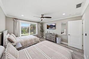 A bedroom with two beds, a dresser, a mirror, and a ceiling fan. - BG North 58 - 2 bed/2Bath - Pool, Tennis, Pickleball, Top Floor - Sleeps 4 (Boca Grande)