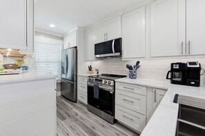 A modern kitchen with white cabinetry, stainless steel appliances, and a marble countertop. - BG North 58 - 2 bed/2Bath - Pool, Tennis, Pickleball, Top Floor - Sleeps 4 (Boca Grande)