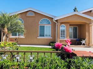 A house with a brown stucco exterior, white window shutters, and a porch with a bench. - Spacious 5-bedroom house San Diego by UCSD La Jolla DelMar CarmelValley Qualcomm (San Diego)