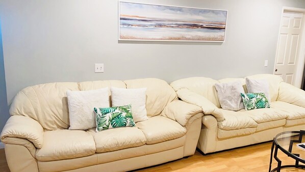 A beige sectional sofa with white and green pillows, a painting above, and a door to the right. - Spacious 5-bedroom house San Diego by UCSD La Jolla DelMar CarmelValley Qualcomm (San Diego)