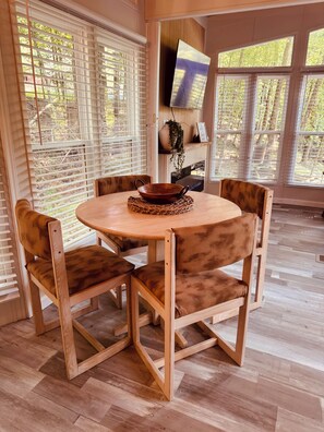 A dining area with a round wooden table, four chairs, and a woven placemat.