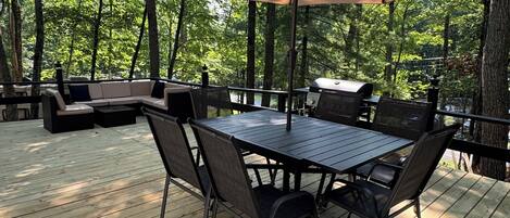 An outdoor deck with a table and chairs, surrounded by trees.