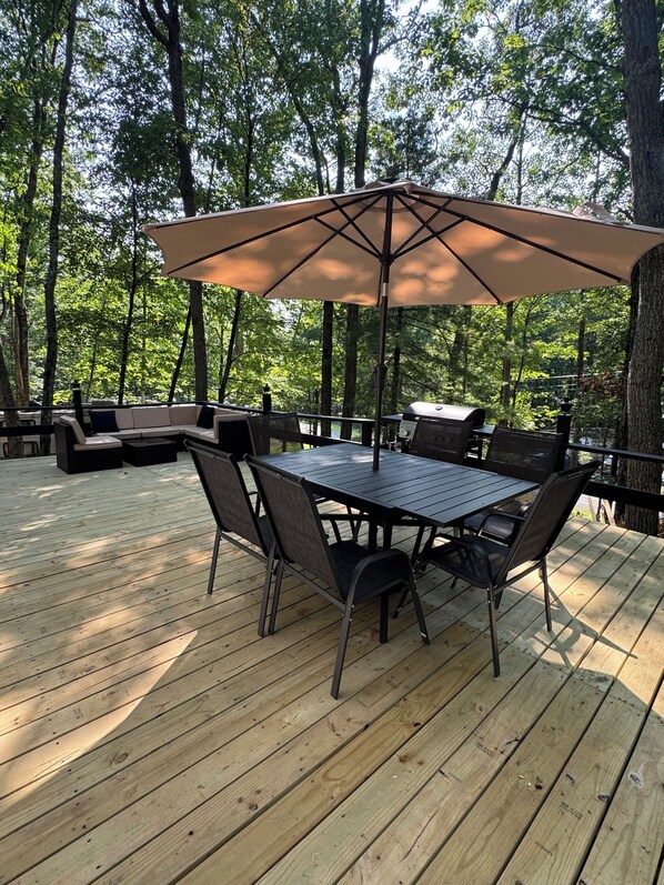 An outdoor deck with a table and chairs, surrounded by trees.
