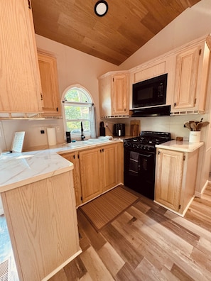 A kitchen with wooden cabinets, a black stove, and a microwave. - Perfect Nature Getaway Awaits!
Relax, enjoy a peaceful stay surrounded by nature (Milford)