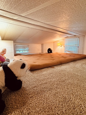 An attic room with a large, plush, brown sofa, a stuffed panda toy, and a ceiling fan. - Perfect Nature Getaway Awaits!
Relax, enjoy a peaceful stay surrounded by nature (Milford)