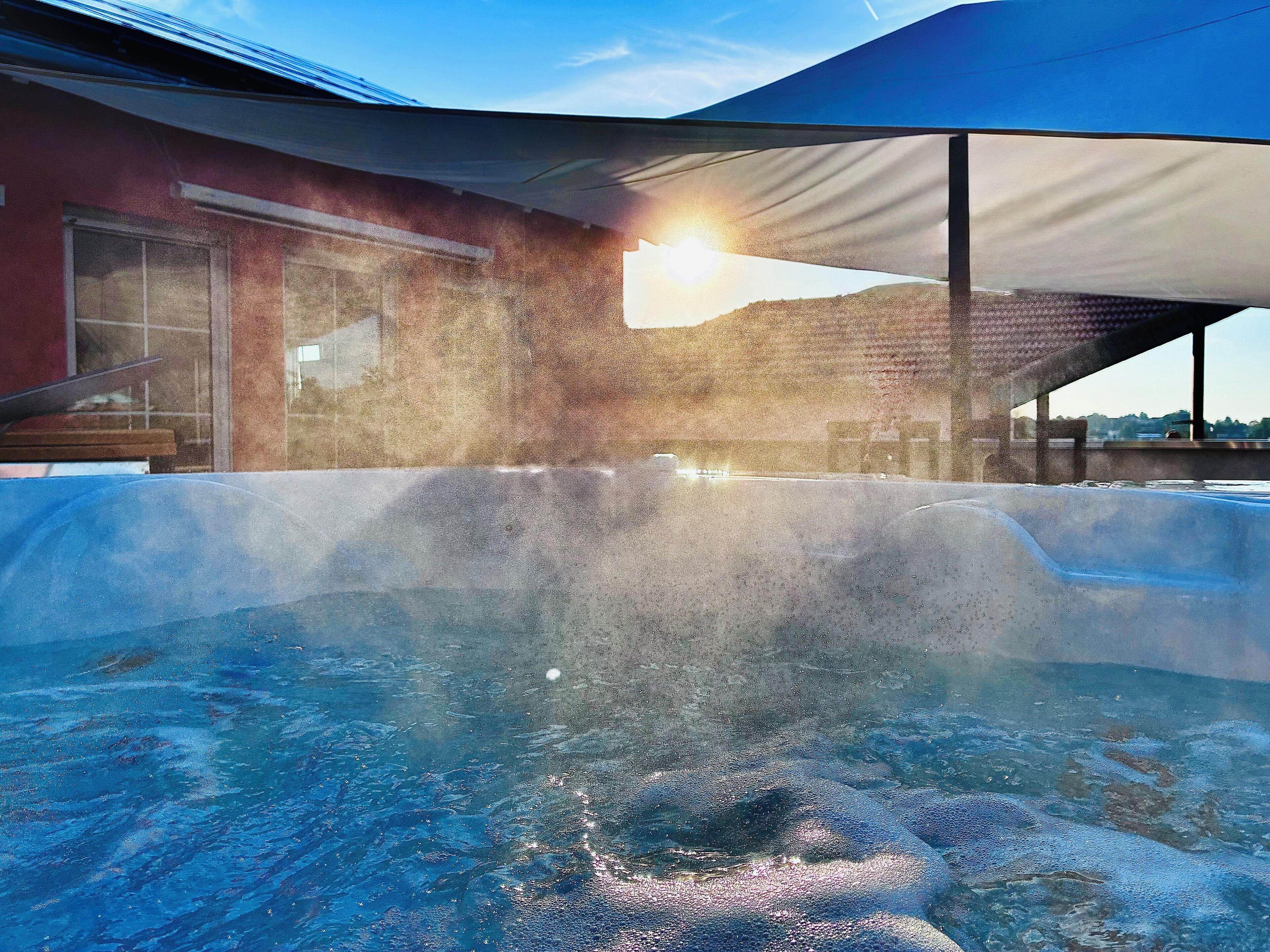 A hot tub with a clear view of the sky and a building in the background.