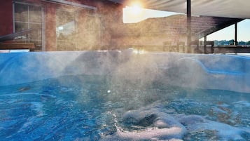 A hot tub with a clear view of the sky and a building in the background.