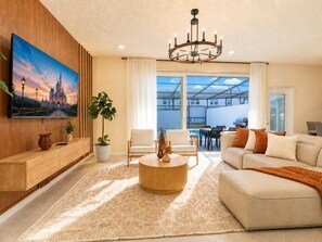 A modern living room with a large flat-screen TV, a round coffee table, and a sofa. - Retiro Moderno 5BR Windsor Cay | Piscina Privada + Sala de Jogos (Clermont)