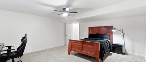 A bedroom with a single bed, a desk, a chair, a ceiling fan, and a floor lamp.