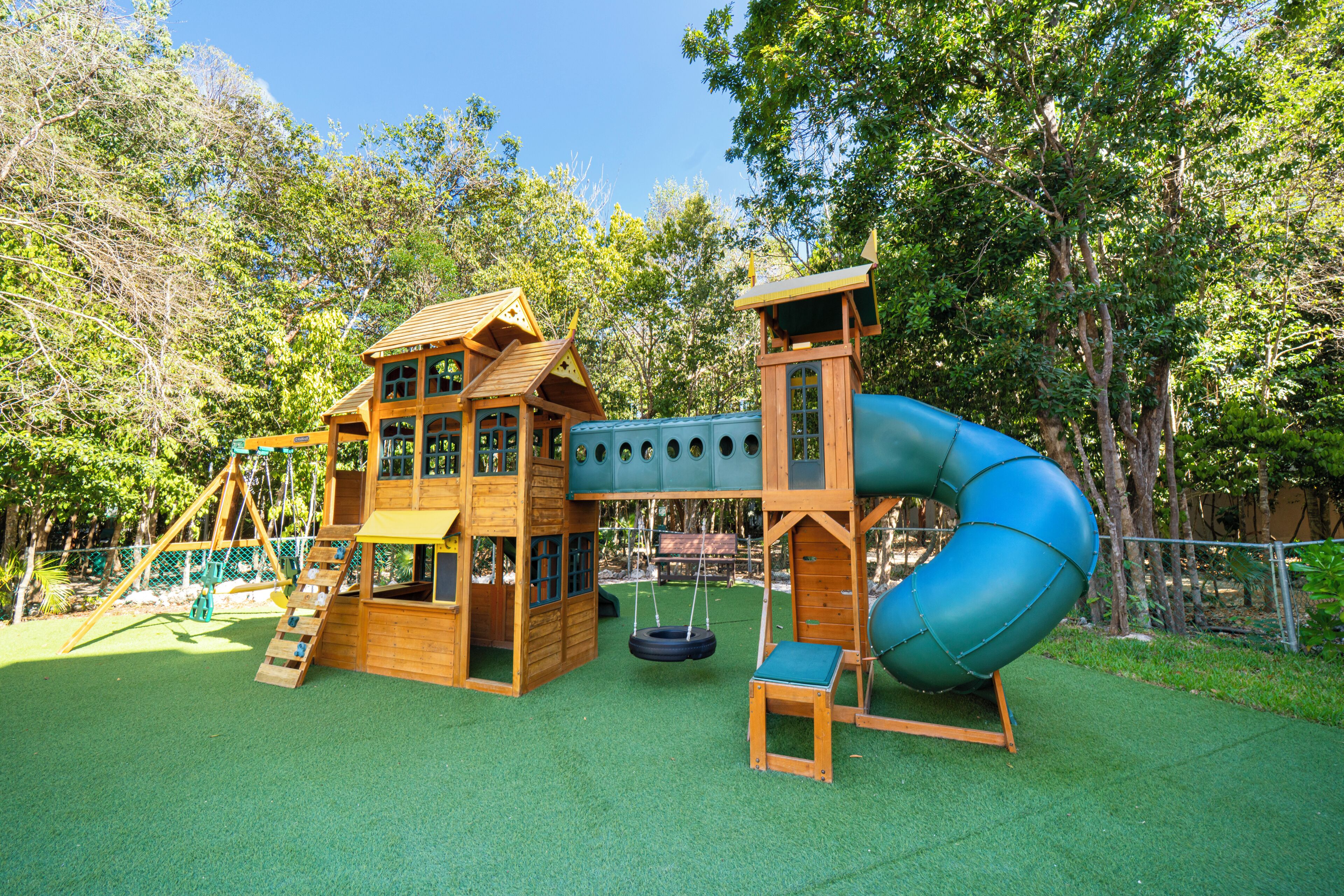 Una casita de madera con un tobogán y un columpio en un parque.