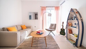 A living room with a sofa, a coffee table, a chair, a bookshelf, and a guitar. - Apartment in Pto. Morelos Rooftop (Puerto Morelos)