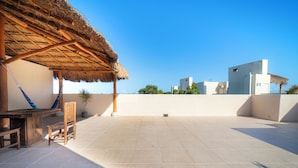An outdoor patio with a thatched roof, a wooden bench, and a hammock. - Apartment in Pto. Morelos Rooftop (Puerto Morelos)