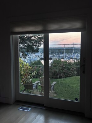 A room with a large sliding glass door leading to a garden with a lawn, a wooden table, and chairs. - Waterfront 3 Bedroom Marina Retreat • East Hampton • HeatedPool (East Hampton)
