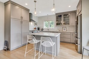 A modern kitchen with a central island, two bar stools, and a built-in oven. - Waterfront 3 Bedroom Marina Retreat • East Hampton • HeatedPool (East Hampton)