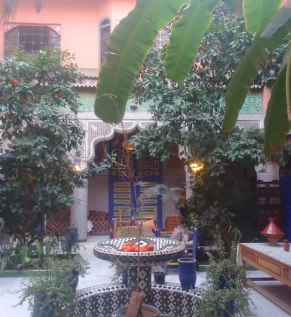 A courtyard with a central fountain, surrounded by lush greenery and traditional architecture. - Riad zaida (Marrakech)