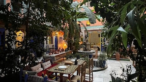 Un patio con zona de comedor, asientos y una fuente.