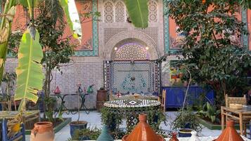 A courtyard with a fountain, potted plants, and traditional Moroccan tiles.