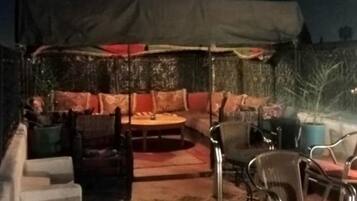 Un espace extérieur aménagé avec un coin salon abrité, un canapé et une table à manger.