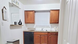 Una cocina funcional con lavavajillas, un lavamanos y armarios de madera.