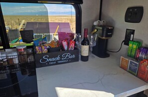 A snack bar area with a wine bottle, snacks, and a coffee machine.