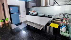 A modern kitchen with a black countertop, white cabinets, and stainless steel appliances.