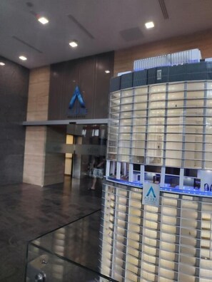 A modern building with a glass facade, a prominent logo on the wall, and a reception desk with a sign.