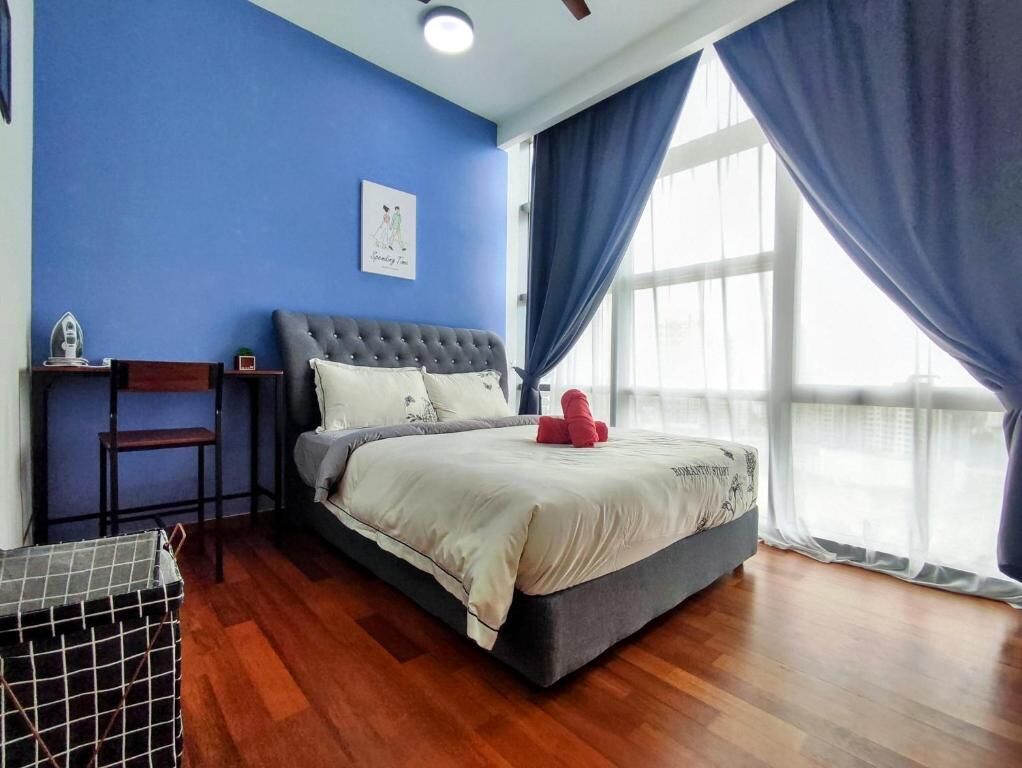 Un dormitorio con cama, mesita de noche, silla y ventana con cortinas.
