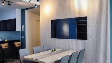 A modern dining area with a long table, chairs, and a ceiling fan.