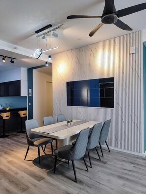 A modern dining area with a long table, chairs, and a ceiling fan.