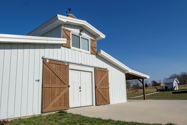 A white building with a gabled roof, a large garage door, and a small attached structure.