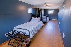 Ein Schlafsaalzimmer mit Stockbetten, Wäscheständer und Mülleimer.